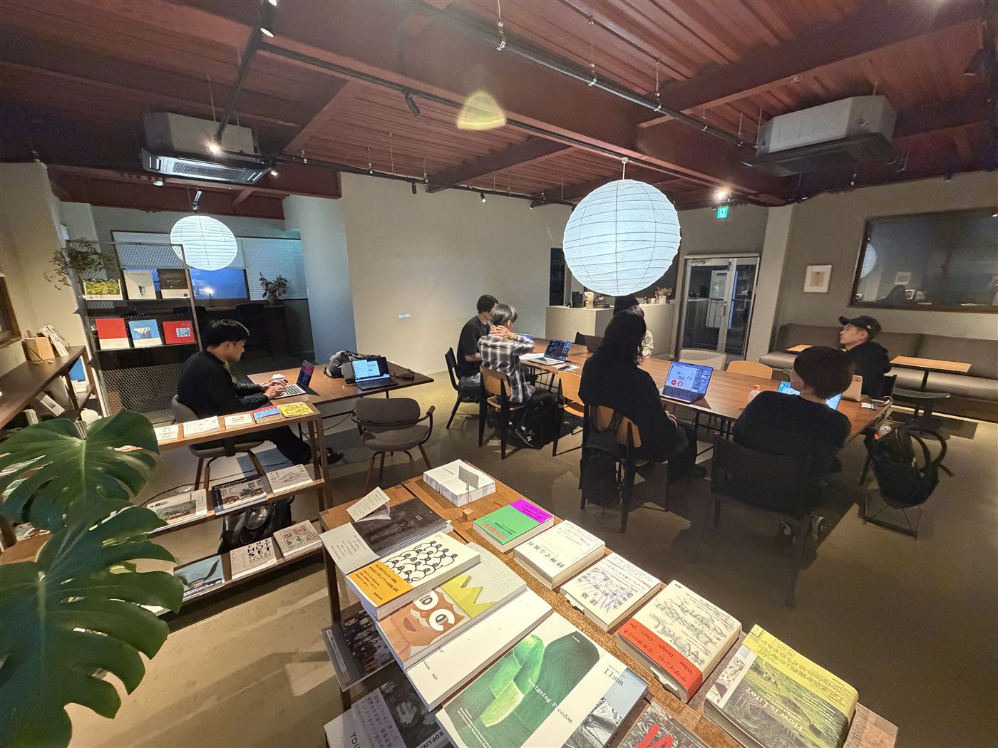 本と植物に囲まれた somewhere の店内。長いテーブルで、参加者がノートパソコンを開いている
