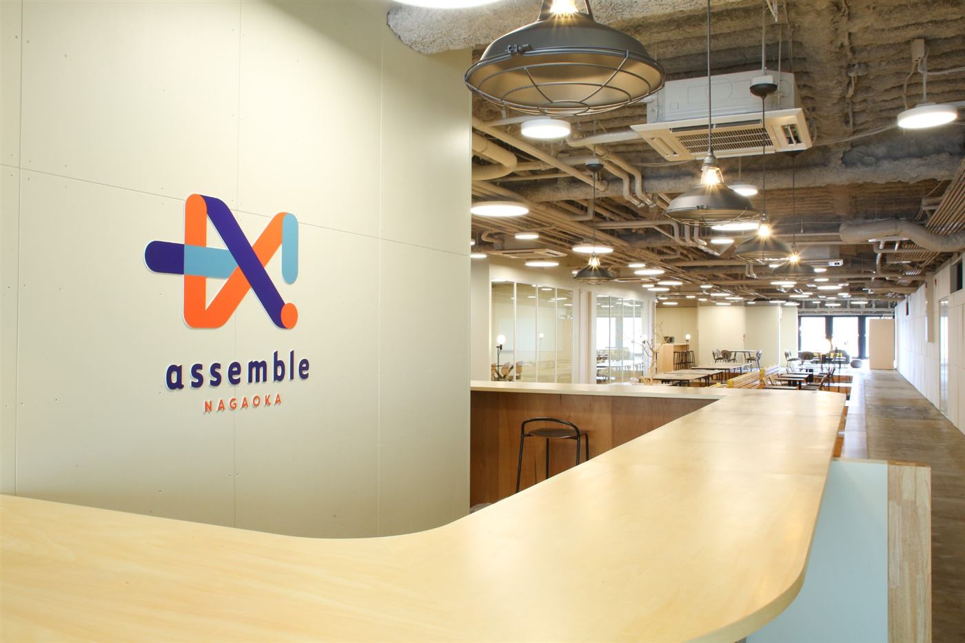 assemble長岡の入口。壁のロゴと、木のカウンター