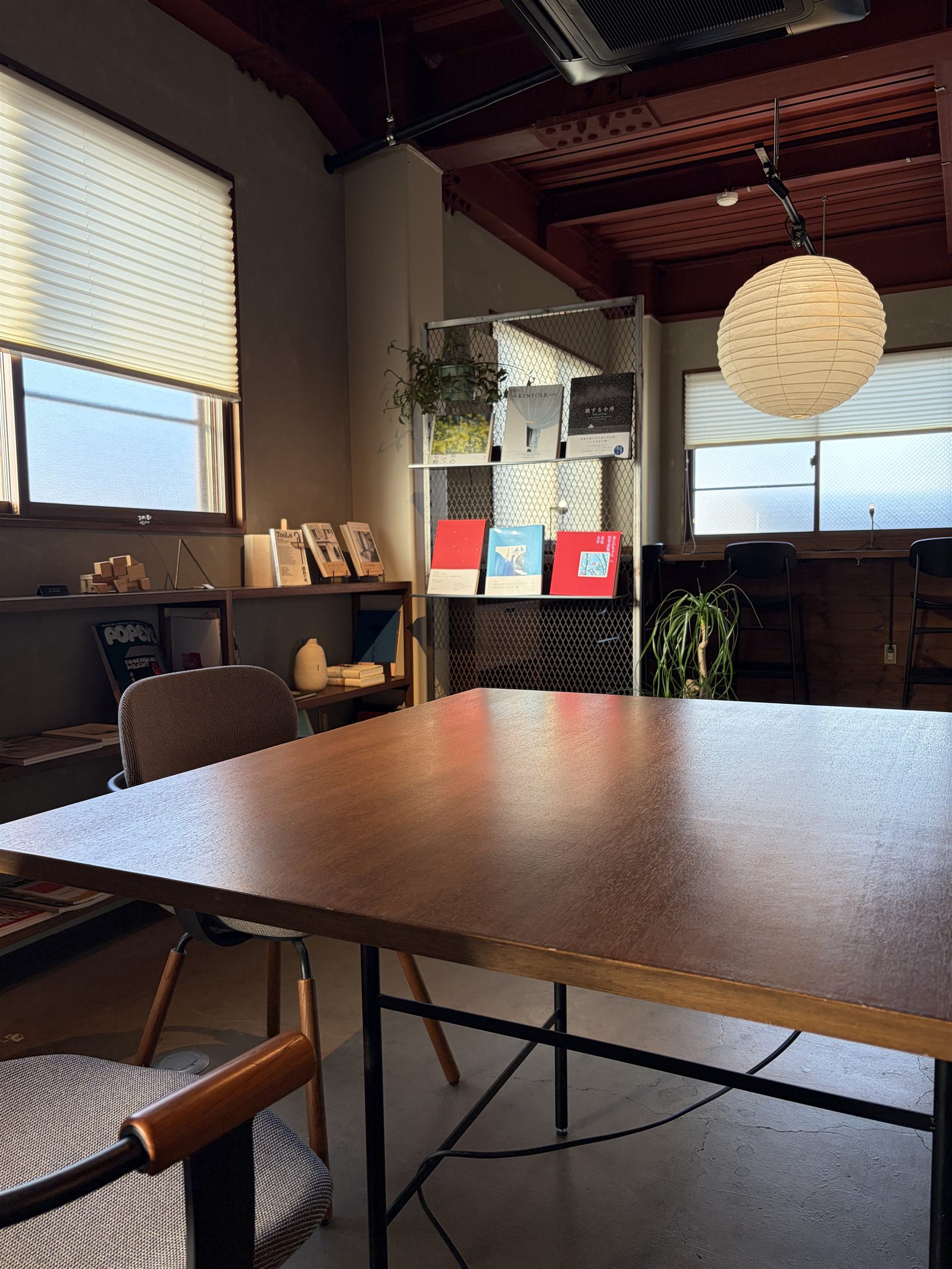 somewhereの店内。木のテーブルと椅子、本棚、丸い和紙の照明